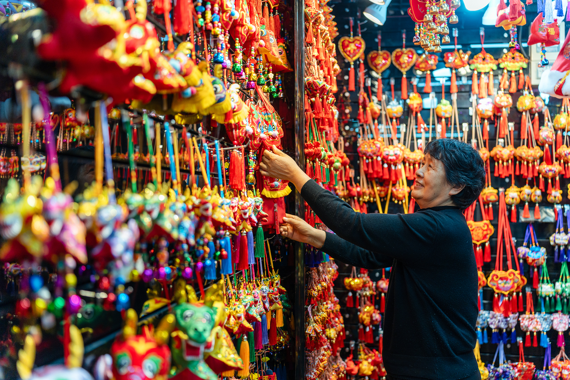 2023年12月11日，金華義烏國(guó)際商貿(mào)城，龍年喜慶用品掛滿攤位，顧客正在挑選中。