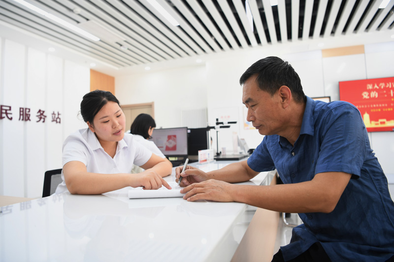 2023年5月23日，河北雄安新區(qū)容東片區(qū)南文營社區(qū)居民（右）在社區(qū)便民服務(wù)站辦理業(yè)務(wù)。